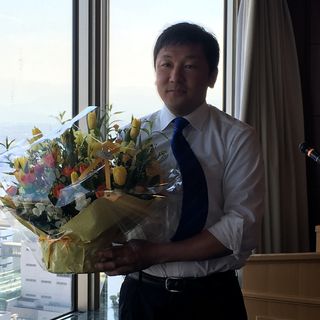 支援者の方から頂いた花を両手に記念撮影する吉田豊史